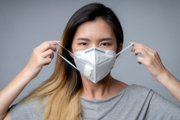 Young woman wearing surgical mask, studio shot