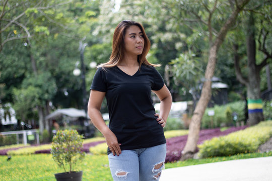 Woman wearing black t shirt in a park, suitable for mock up template, background. etc