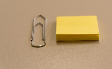 Paper clip and yellow paper pad on an office table