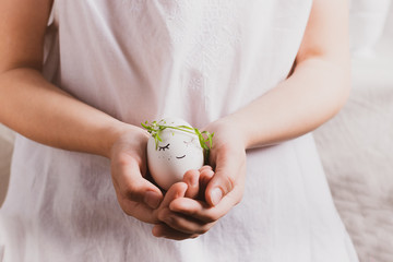 Festive composition Easter egg with a funny muzzle with eyes in the hands child. Happy easter concept. Horizontal frame