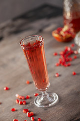 Pomegranate wine, seeds and pomegranate fruit on wooden background