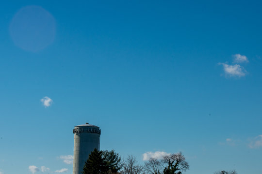 A Far Off Shot of a Water Tower in Elkins Park With a Blue Sky in the background and very few clouds.