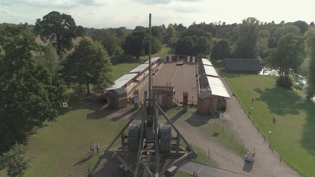 Aerial crane shot moving down behind trebuchet overlooking firing range