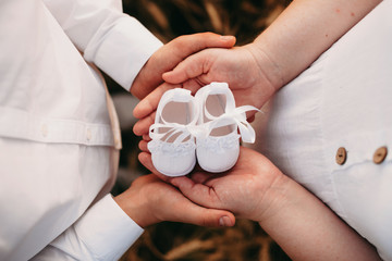 Lovely caucasian couple holding a pair of baby shoes while posing close to each other