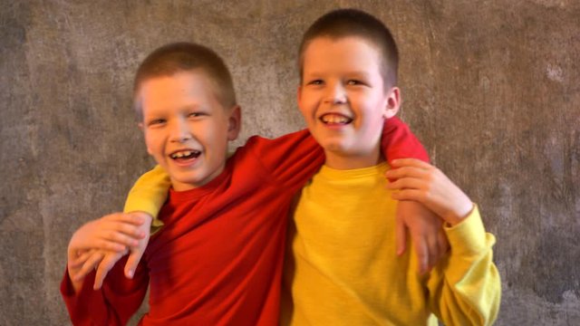 Cute blond boys in yellow and red clothes are busy with themselves and each other. Children try to sing and express their emotions with gestures. Teens are happy together on vacation at home
