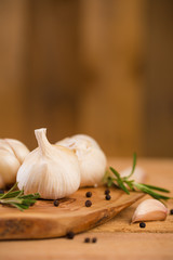 Fresh garlic with spices on a wooden background, thyme and rosemary. Culinary background, ingredients for marinade, close up. Vertical frame