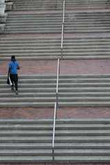 An African American man climbs a long flight of stairs.