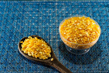 Yellow corn hominy served in bowl on a blue background