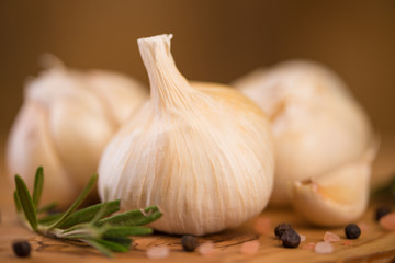Garlic with rosemary and thyme and spices on a wooden background