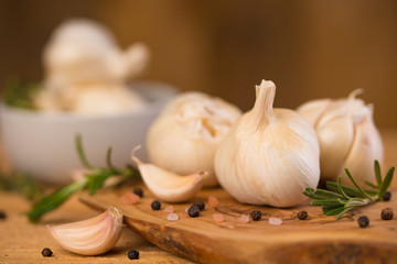 Fresh garlic with spices on a wooden background, thyme and rosemary. Culinary background, ingredients for marinade, closeup
