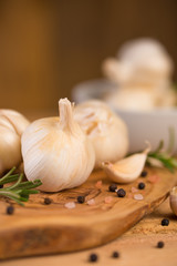 Fresh garlic with spices on a wooden background, thyme and rosemary. Culinary background, ingredients for marinade, close up. Vertical frame