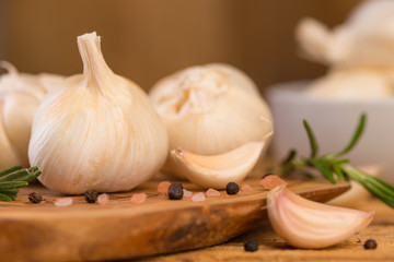 Spicy fresh garlic with rosemary and thyme and black pepper. Culinary splash, on a wooden background.