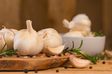 Garlic with rosemary and thyme and spices on a wooden background