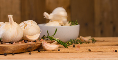 Garlic with rosemary and thyme and spices on a wooden background