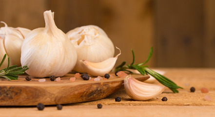 Garlic with rosemary and thyme and spices on a wooden background
