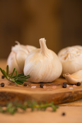 Fresh garlic with spices on a wooden background, thyme and rosemary. Culinary background, ingredients for marinade, close up. Vertical frame