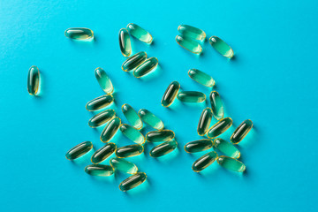 a scattering of yellow transparent fish oil capsules on a blue background. medical background