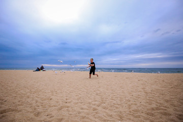 Young boy eating ice cream on the beach surrounded by seagulls 