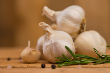 Garlic with rosemary and thyme and spices on a wooden background