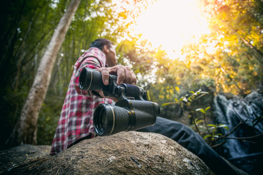 Close up man hand holding watching using binoculars in forest, Travel concept