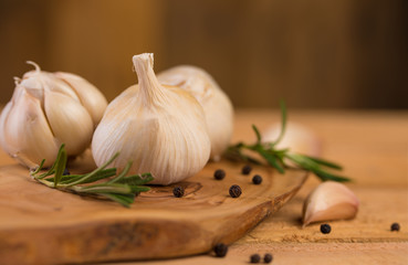 Spicy fresh garlic with rosemary and thyme and black pepper. Culinary splash, on a wooden background.