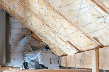 Worker man in overalls working with rockwool insulation material