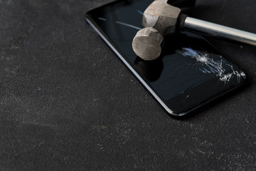 Broken mobile phone screen with a big black iron hammer. LCD screen broken, cracked and unusable...