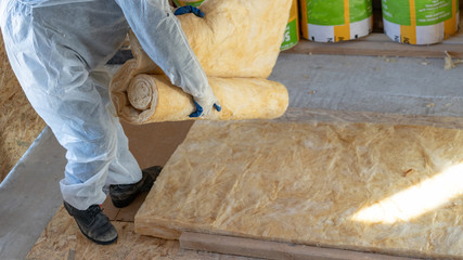 Workman in overalls working with rockwool insulation material