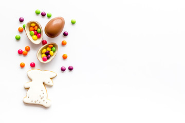 Easter sweets frame. Chocolate eggs and bunny gingerbread on white background top-down frame copy space