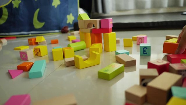 slow motion, happy cute boy playing colorful wooden block toy building in home living room