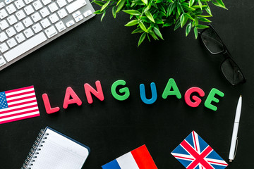 Learn foreign language online. Concept with text, headset and keyboard on black background top-down