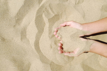Fototapeta na wymiar Sand in hands of girl. Hand strew sand