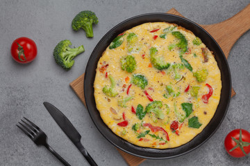Frittata with fresh vegetables. Omelette with broccoli, paprika, tomato and herbs. Top view. 