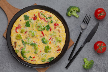 Frittata with fresh vegetables. Omelette with broccoli, paprika, tomato and herbs. Top view. 