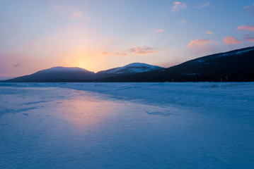 Ice pressure ridge of Kandalaksha bay at sunset. Colorful evening clouds. Mountains and coniferous forests of Kola Peninsula in the background. White sea, Polar circle, Karelia, Russia © Alex Stemmer