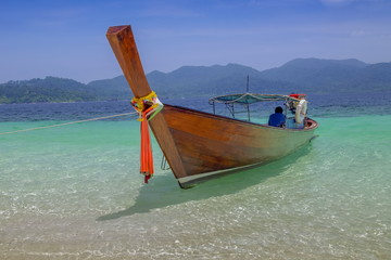 view seaside of a long-tail boat floating in blue-green sea and blue sky background, Monkey island, long-tail boat trip from Lipe island, Satun, southern Thailand.