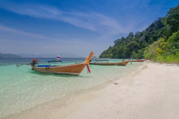 Fototapeta na wymiar view seaside of a long-tail boat floating in blue-green sea and blue sky background, Monkey island, long-tail boat trip from Lipe island, Satun, southern Thailand.
