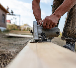 A worker saws a wooden beam.