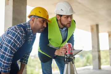 Two engineers on the construction use working equipment.