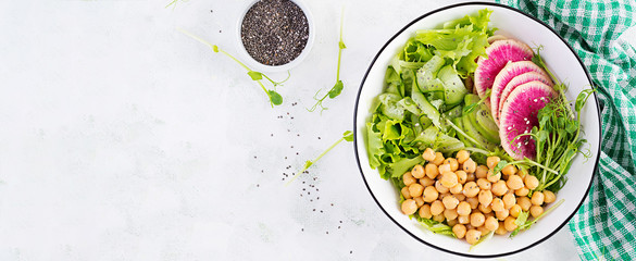 Trendy salad. Vegan Buddha bowl with chickpeas, watermelon radish, cucumber and peas sprouts. Healthy balanced eating. Top view, overhead, banner