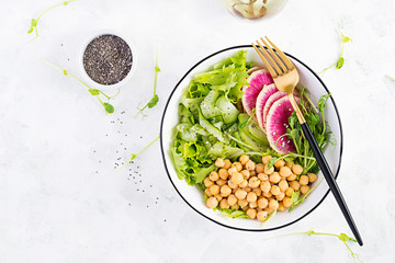 Trendy salad. Vegan Buddha bowl with chickpeas, watermelon radish, cucumber and peas sprouts. Healthy balanced eating. Top view, overhead, flat lay