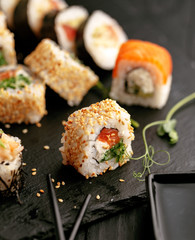 Traditional Japanese sushi food rolls on a black wooden background
