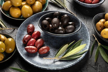 Olives, green, black and red, an assortment with leaves on a black background