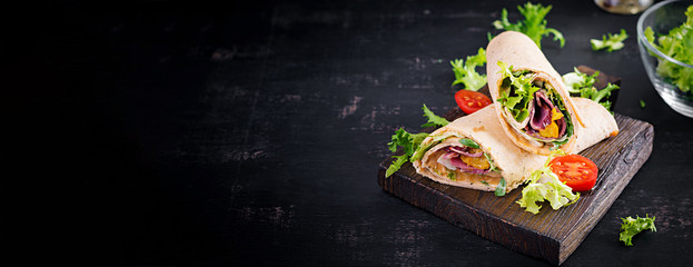 Fresh tortilla wraps with ham beef and fresh vegetables on wooden board. Beef burrito. Mexican cuisine. Banner