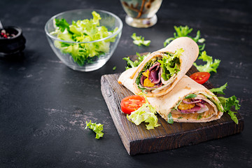 Fresh tortilla wraps with ham beef and fresh vegetables on wooden board. Beef burrito. Mexican cuisine. Copy space