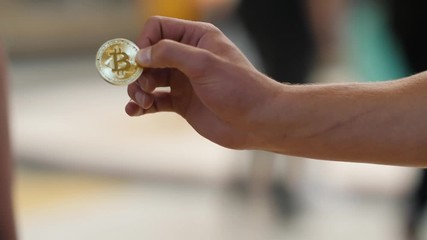 Girl is holding bitcoin and passes it to girl. Close up shot on girl as she holds bitcoin and gives it to the boy. - Powered by Adobe