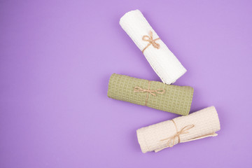 Three-folded into a roll and tied with a rope towels on a purple background.
