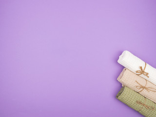 Three tied towels on a purple background.