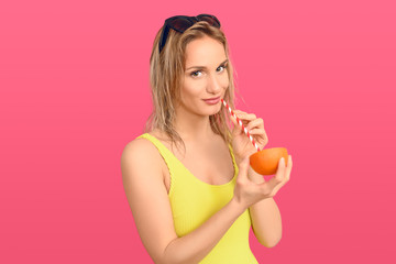 Woman drinking through a straw from an orange