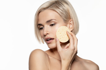 Woman with  using round cosmetic face sponge.